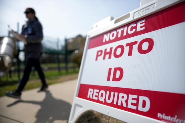 Super Tuesday voter walking past a sign requiring a photo ID at a polling location in Mount Holly, N.C., on March 5, 2024