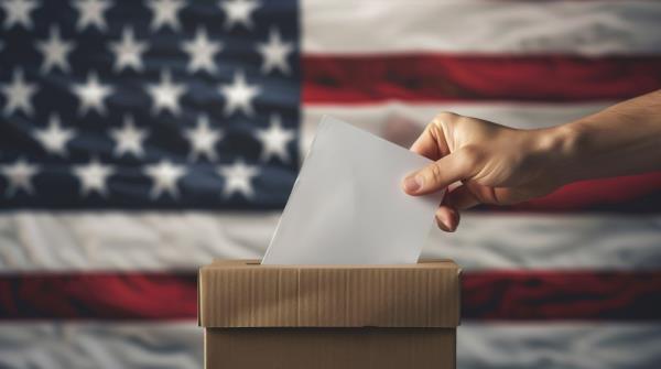 A hand placing a voting ballot into a United States election box